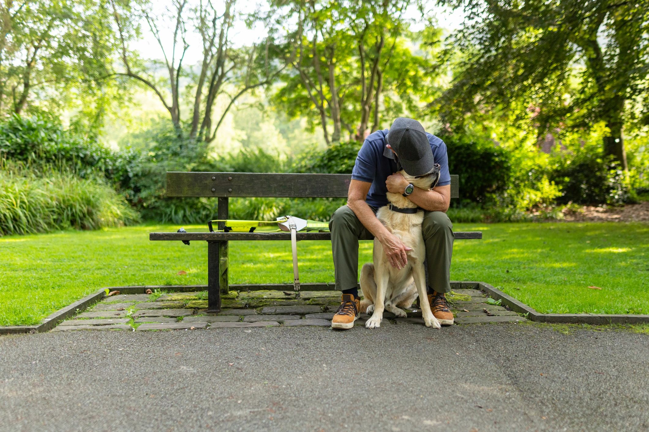 Man hugging his service dog on a park bench